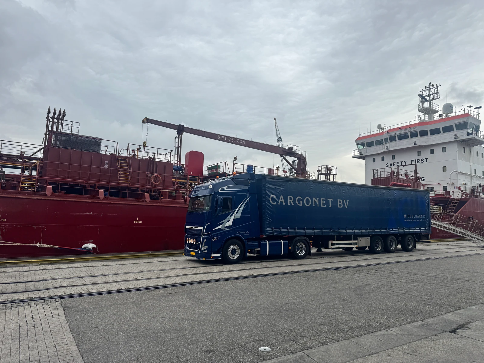Vrachtwagen met Cargonet op de oplegger langs een schip in de haven.