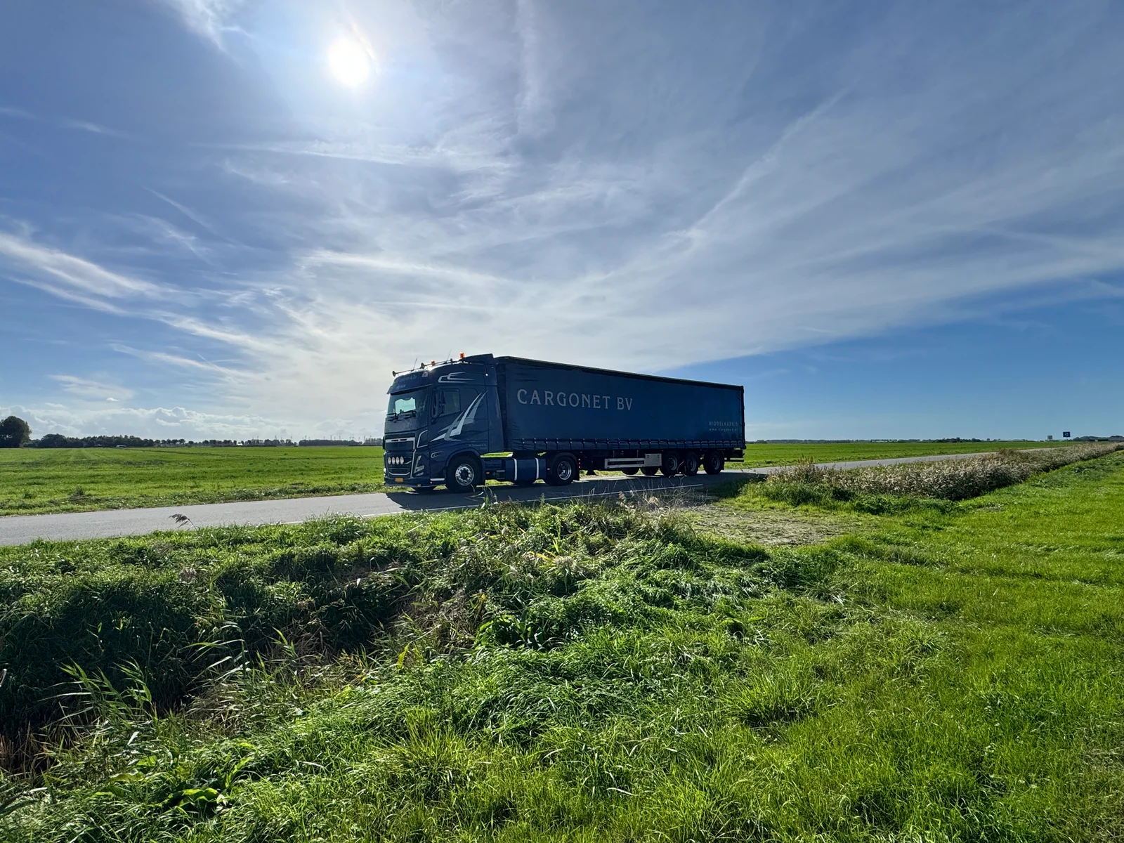 Vrachtwagen met Cargonet op de oplegger in een open polderlandschap.