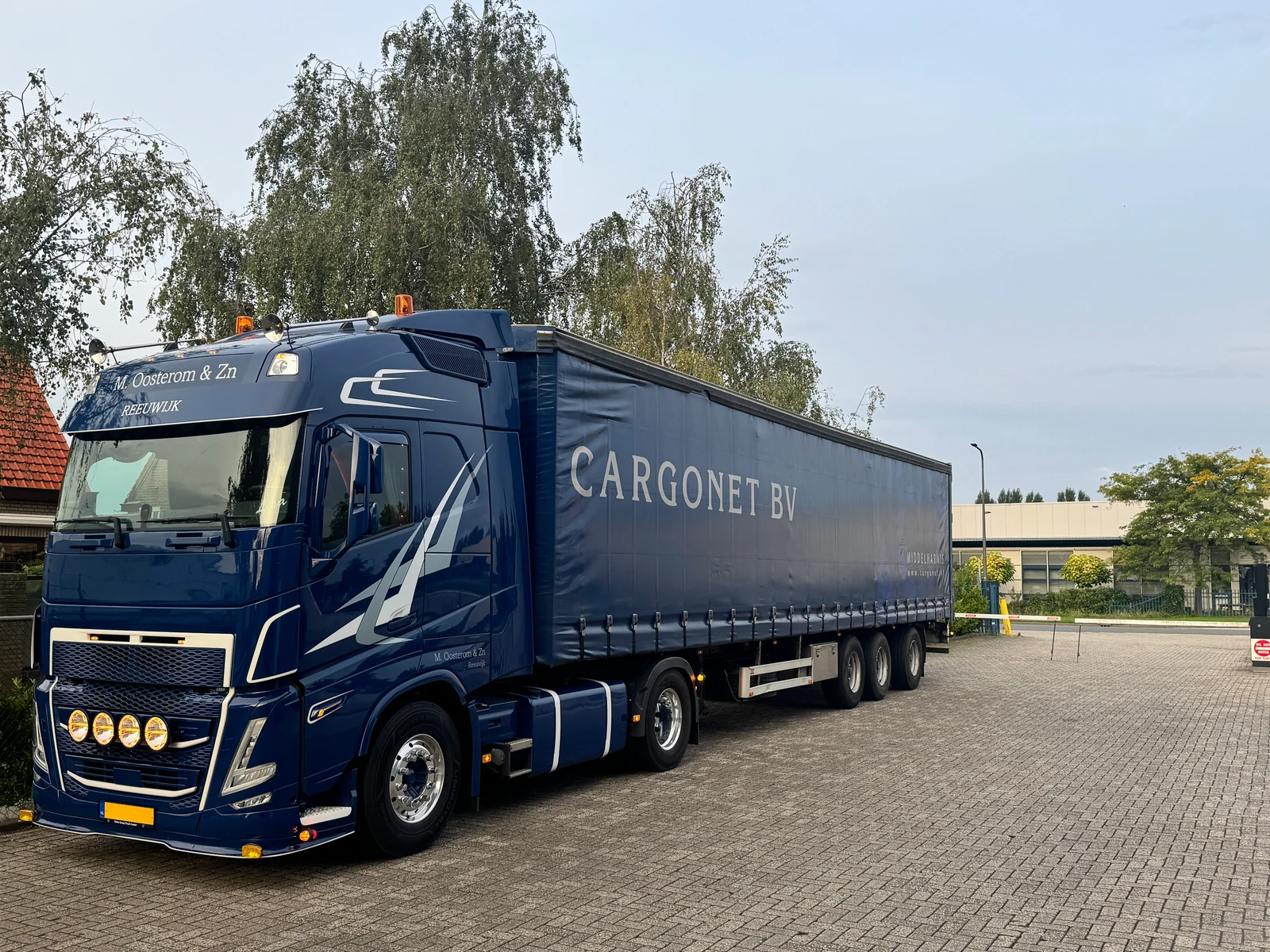 Blauwe vrachtwagen met Cargonet op de oplegger op een bedrijfsterrein.