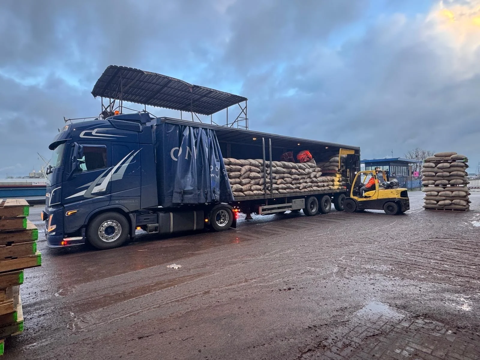 Tautliner van een vaste charter met geopend schuifzeil, tijdens laden of lossen met een heftruck.